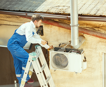 Man working on house aircone on the outside